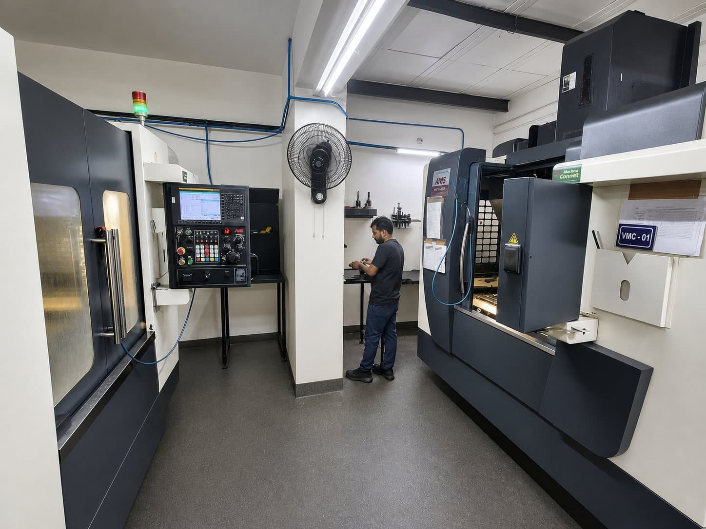 Symtech machine shop with two vertical machining centres and an operator at a tool bench
