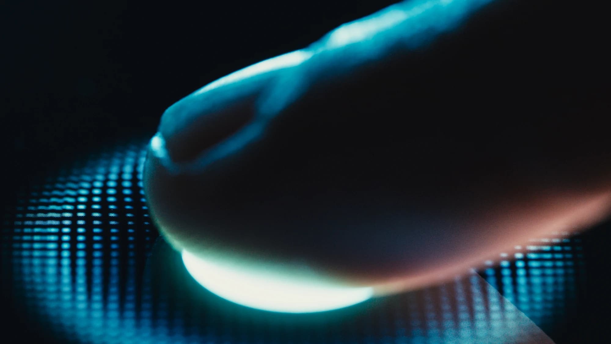 Close-up of a fingertip on an illuminated fingerprint scanner