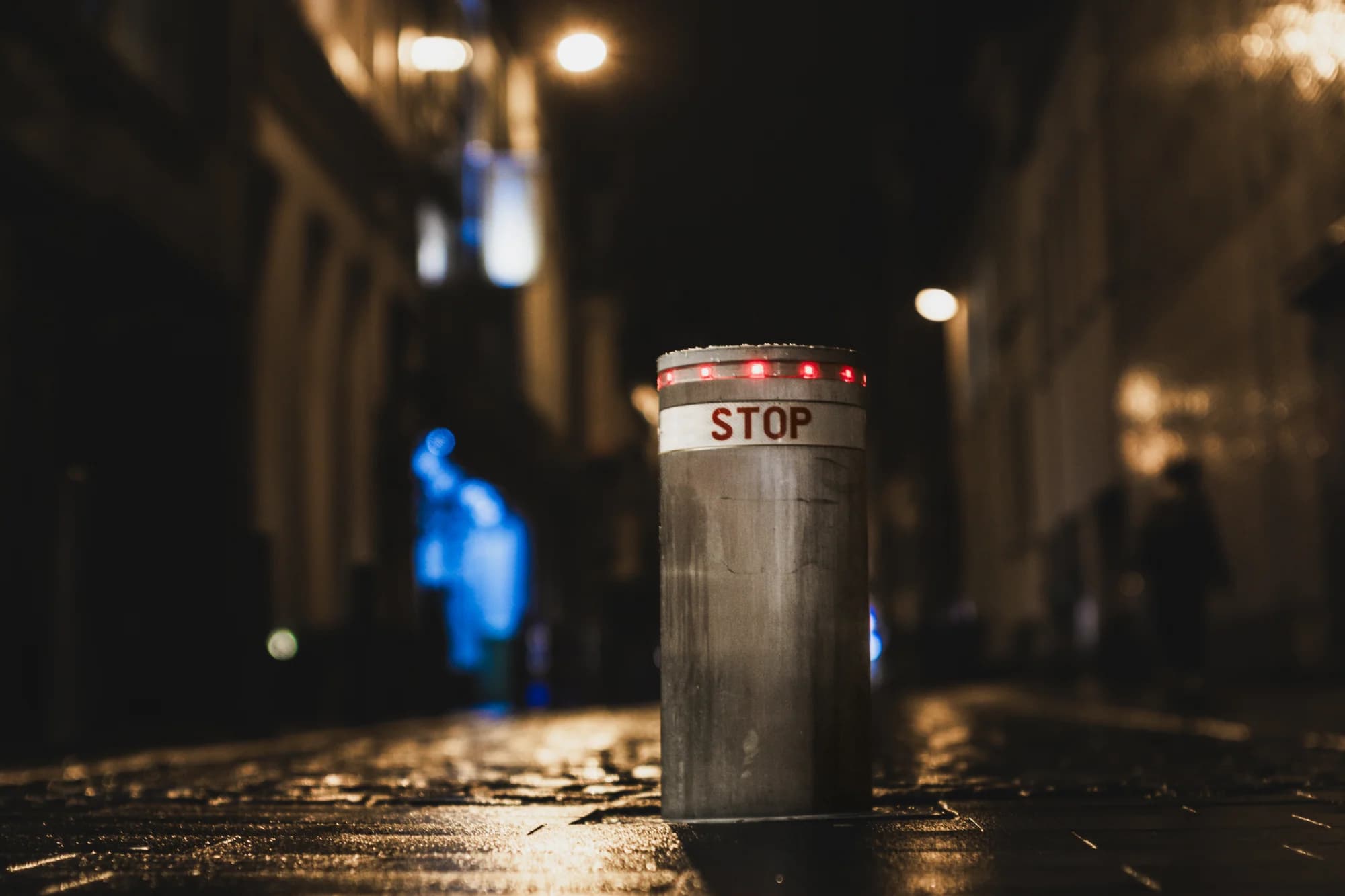 Retractable steel bollard with red warning lights at night
