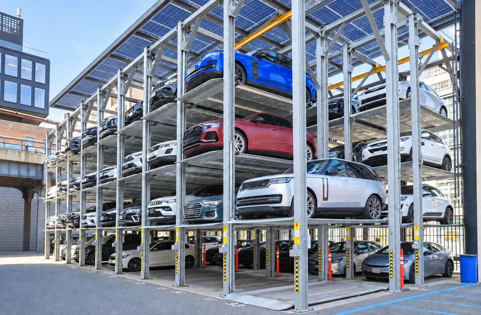 Multi-level puzzle parking platforms with cars beneath a solar canopy