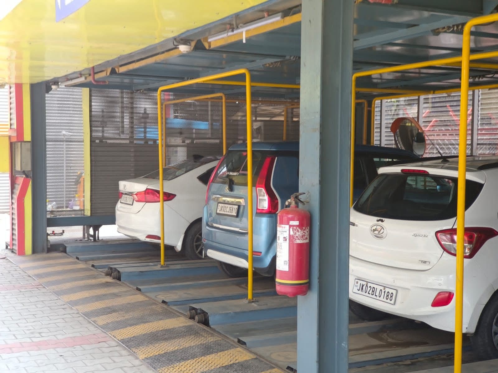 Puzzle parking pallets with guard rails holding three cars, steel columns behind