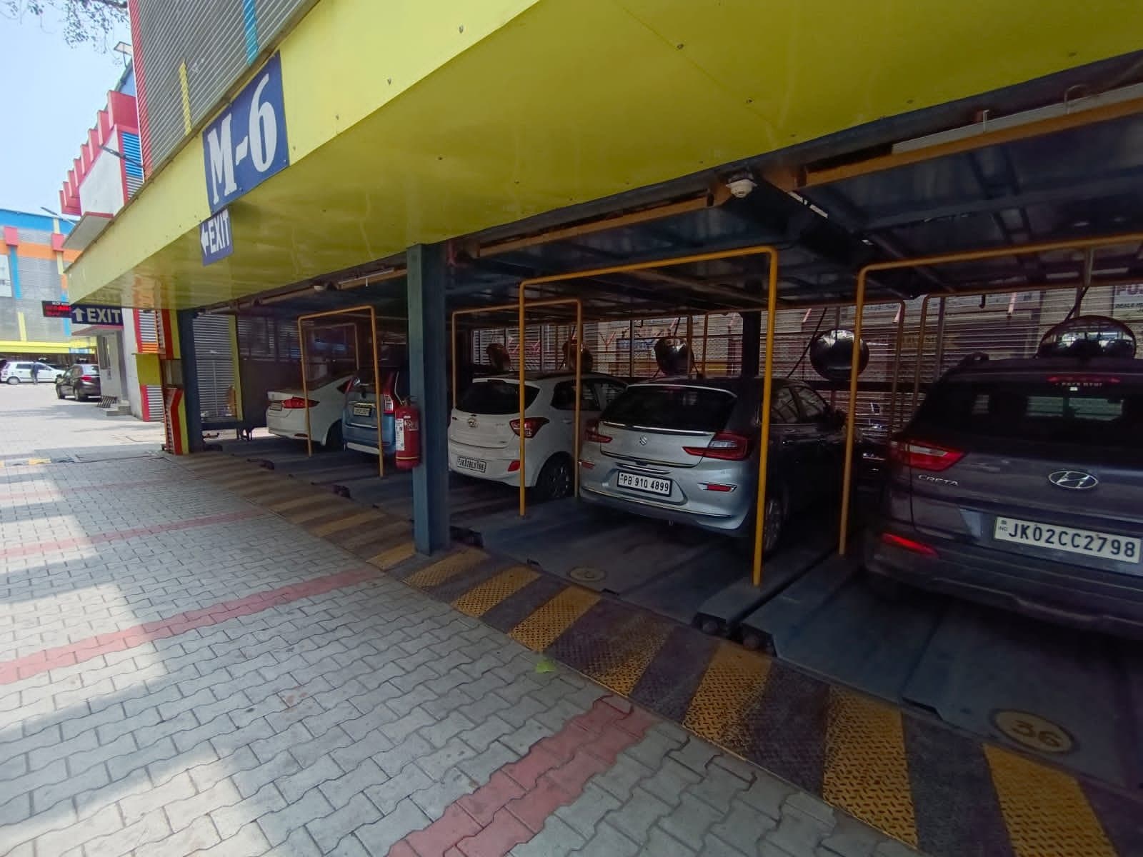 Ground level of a multi-level puzzle parking module with sliding pallets carrying cars under yellow guard frames