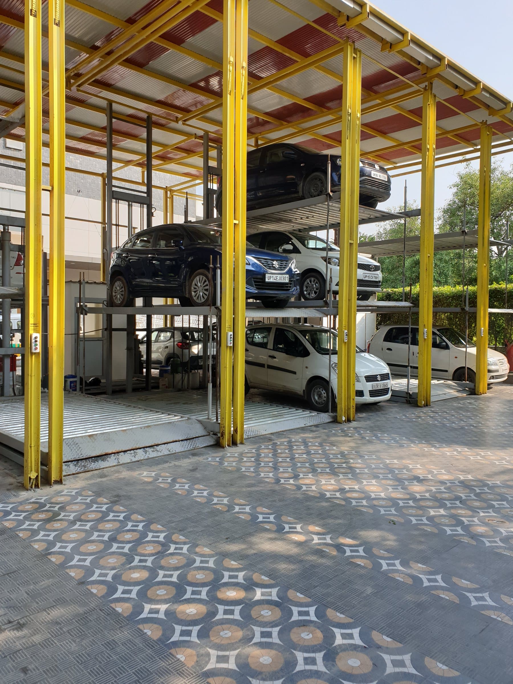 Row of three-level hydraulic stack parking units under a canopy, cars on all three levels