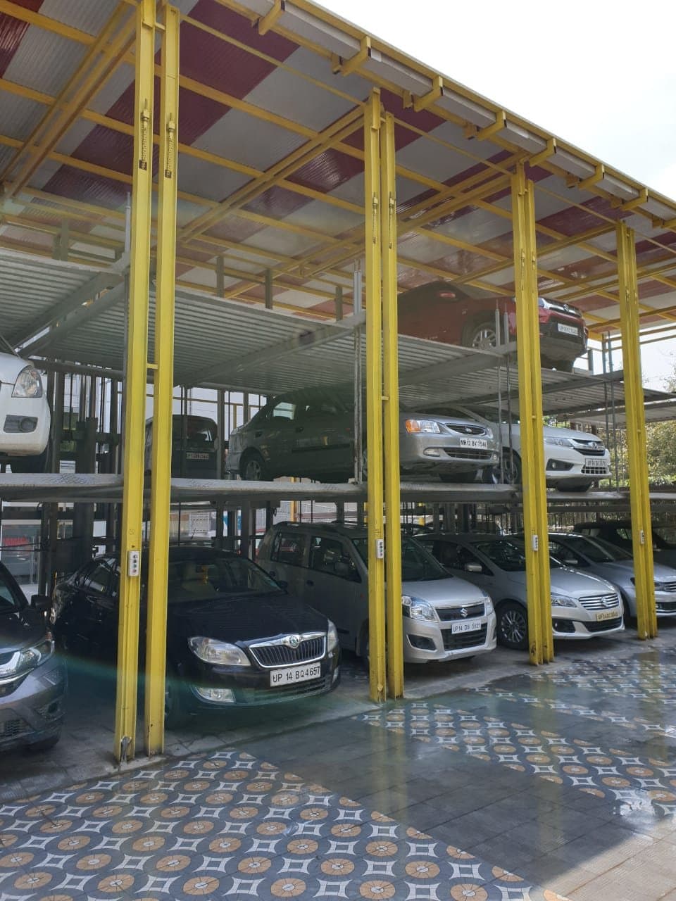 Three-level stack parking with yellow posts, cars on each level, push-button stations on the posts