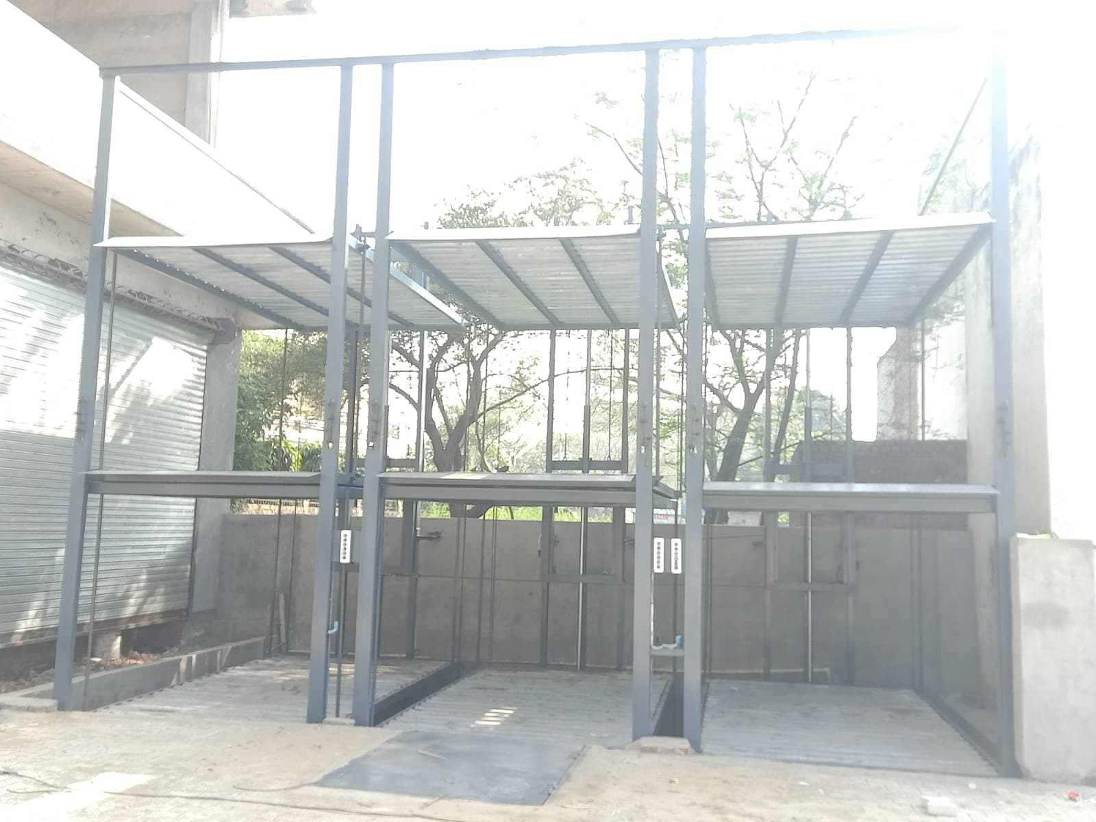 Three bays of three-level stack parking under a canopy, platforms empty