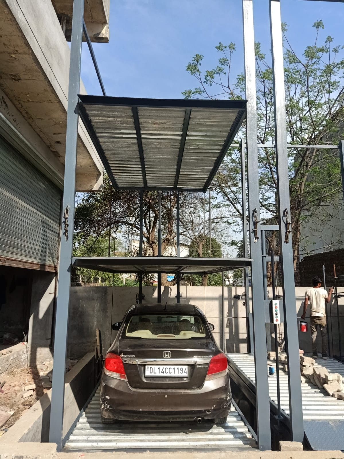 Single three-level stack bay in grey steel with one car on the ground platform and upper platforms raised