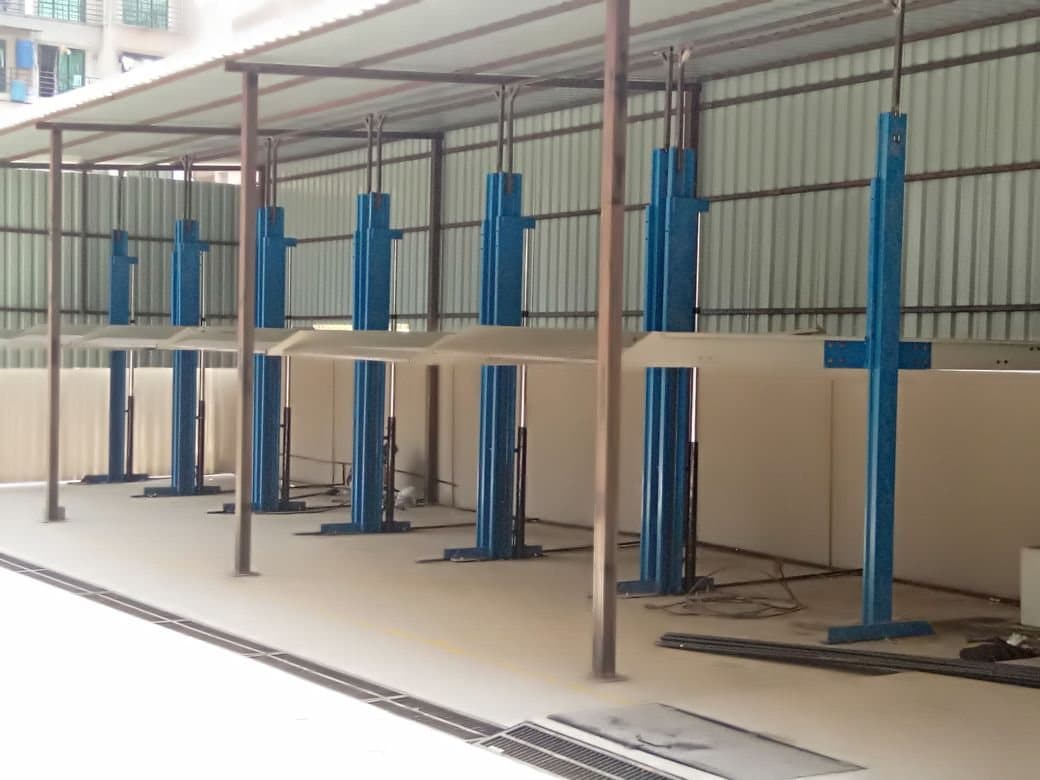Eight two-post stack parking units in a row under a corrugated steel shed, platforms empty