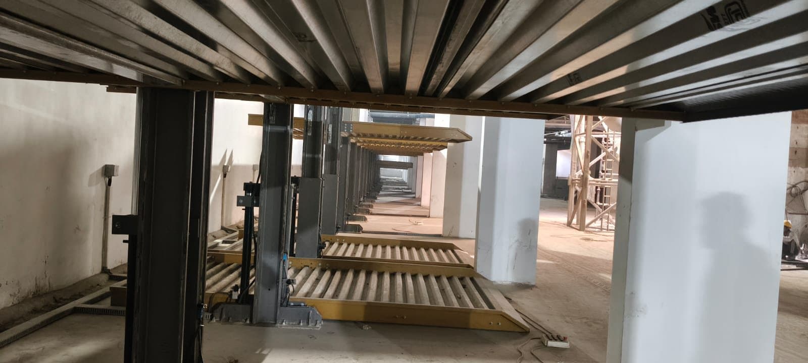 Two-post stack machines erected in a basement under construction, platforms lowered
